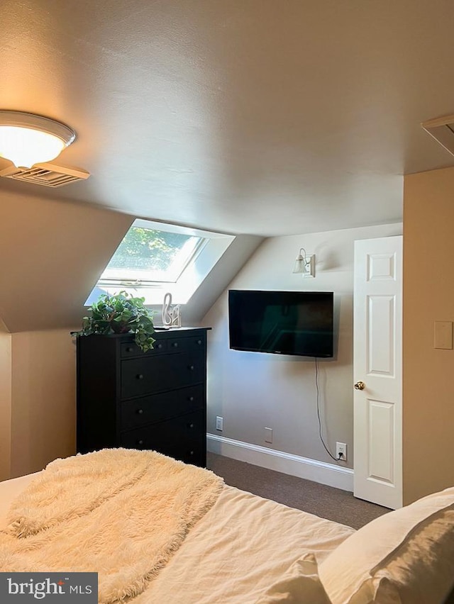 bedroom with dark colored carpet and lofted ceiling with skylight