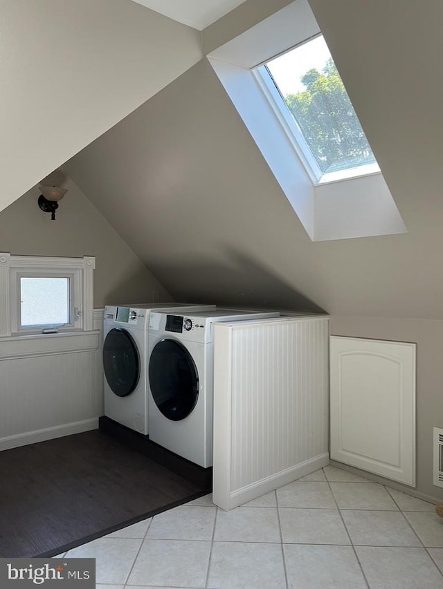 clothes washing area featuring washing machine and clothes dryer, a skylight, and light tile patterned floors