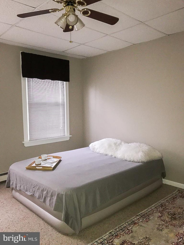 bedroom featuring ceiling fan, carpet floors, and a drop ceiling