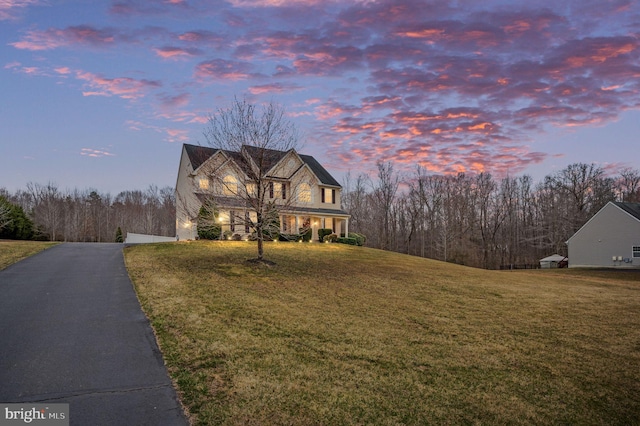 traditional home with aphalt driveway, a lawn, and a garage