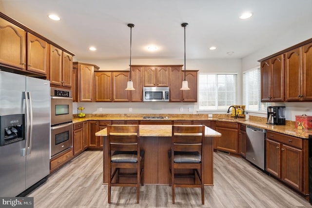 kitchen featuring light wood finished floors, appliances with stainless steel finishes, a breakfast bar area, and a sink