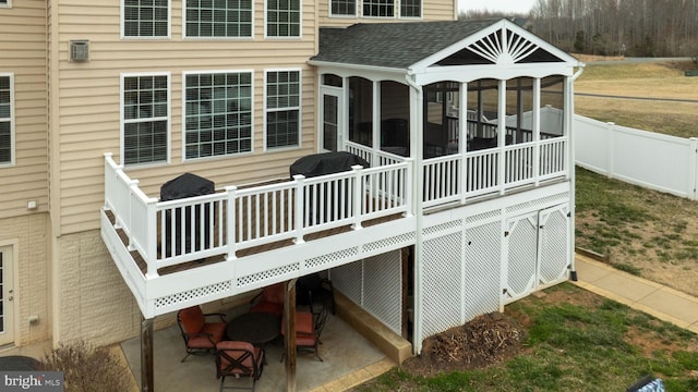 deck featuring a patio area, fence, and a sunroom