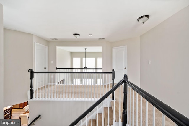 corridor featuring an upstairs landing, visible vents, and baseboards