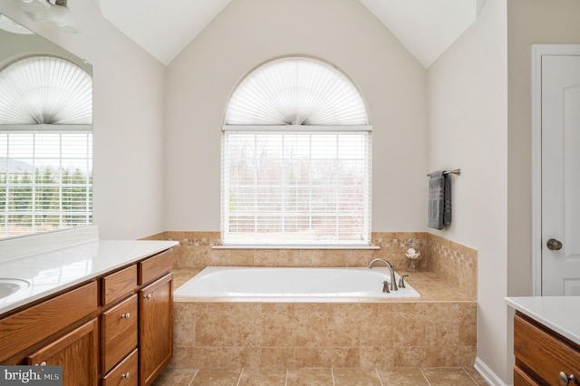 bathroom with a garden tub, vanity, and vaulted ceiling