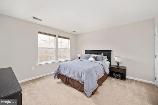 bedroom featuring visible vents, light carpet, and baseboards