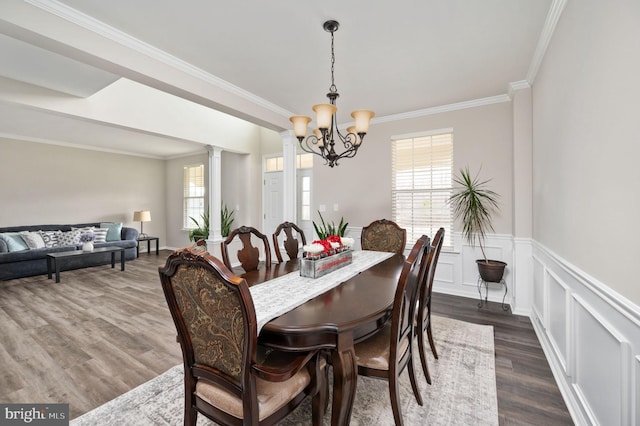 dining area featuring plenty of natural light, dark wood-style floors, decorative columns, and a chandelier