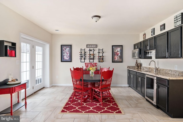 dining room with baseboards, wine cooler, visible vents, and wet bar