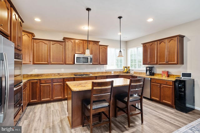 kitchen featuring pendant lighting, a center island, stainless steel appliances, light wood-style floors, and brown cabinetry