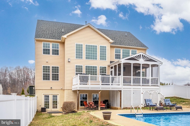 rear view of house featuring a patio area, a fenced in pool, a fenced backyard, and a sunroom