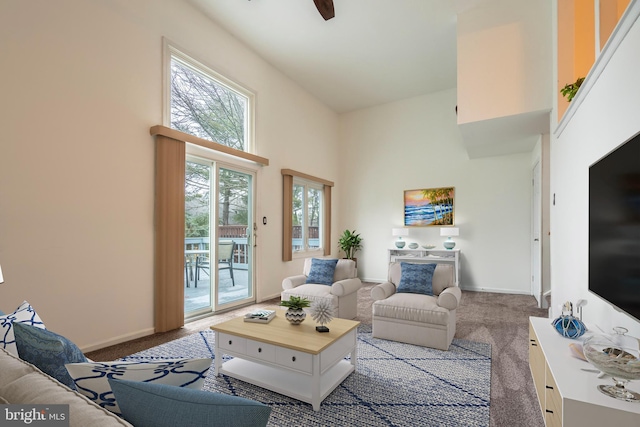 living room with a high ceiling, light colored carpet, and ceiling fan