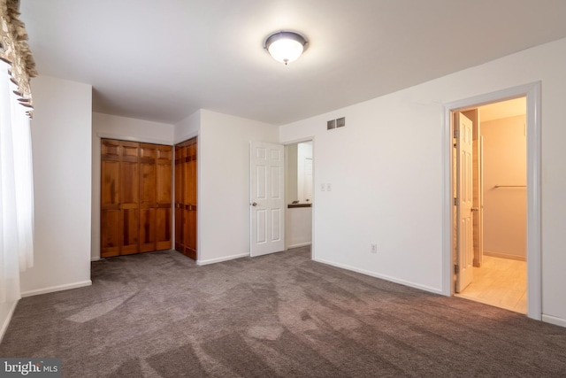 unfurnished bedroom featuring a closet, ensuite bath, and carpet