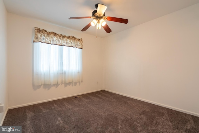 unfurnished room with ceiling fan and dark carpet