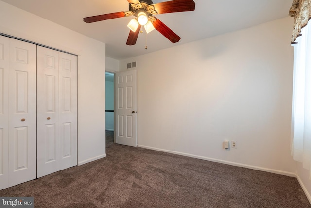 unfurnished bedroom featuring ceiling fan, dark carpet, and a closet