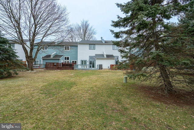 rear view of house with a wooden deck, cooling unit, and a lawn