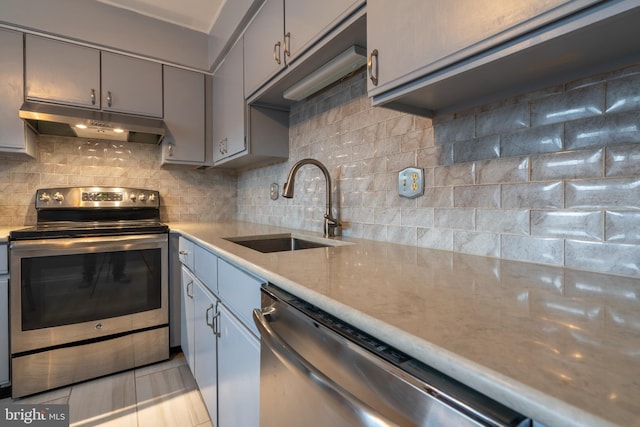 kitchen featuring tasteful backsplash, appliances with stainless steel finishes, gray cabinets, and sink