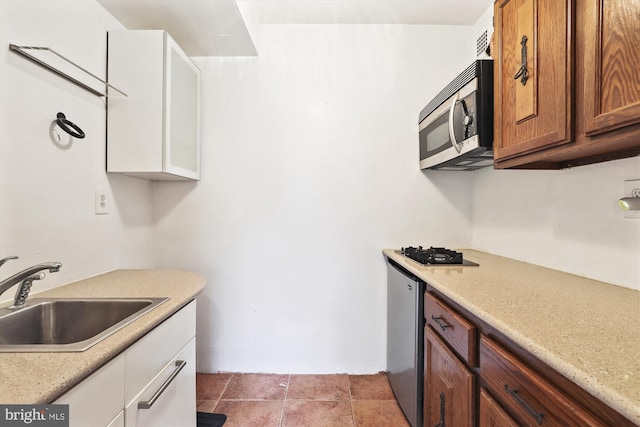 kitchen featuring white cabinetry, sink, and black gas cooktop