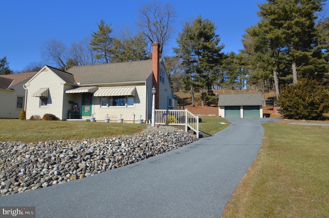 view of front of home with a garage, an outdoor structure, and a front lawn