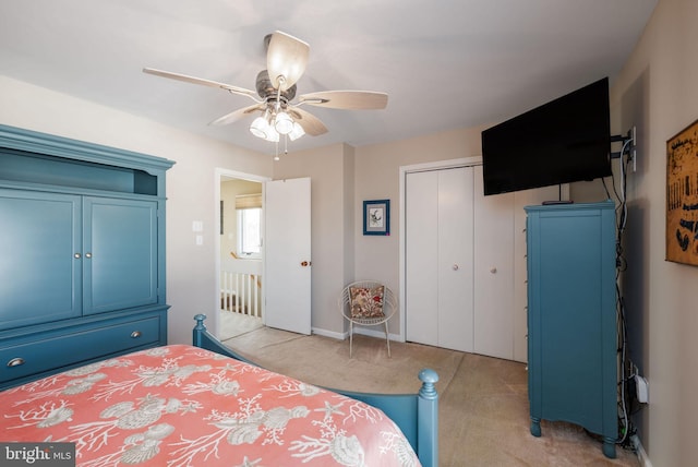 bedroom with light colored carpet, ceiling fan, and a closet