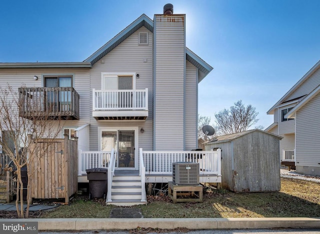 rear view of property with central AC, a balcony, and a storage unit