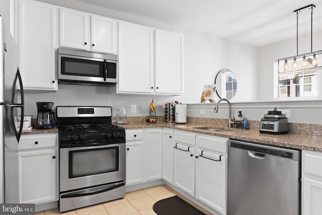 kitchen featuring light tile patterned flooring, appliances with stainless steel finishes, pendant lighting, sink, and white cabinets