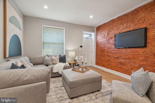 living room with brick wall and light hardwood / wood-style flooring