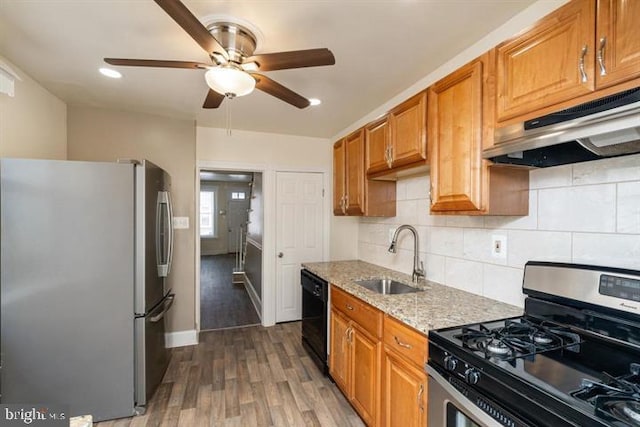 kitchen featuring appliances with stainless steel finishes, dark hardwood / wood-style floors, sink, decorative backsplash, and light stone counters