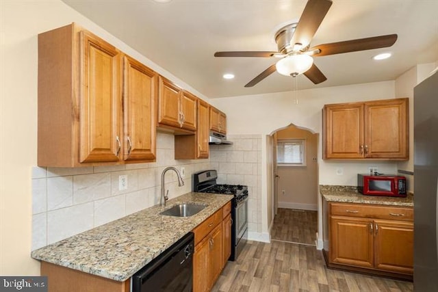 kitchen featuring sink, decorative backsplash, stainless steel appliances, light stone countertops, and light hardwood / wood-style flooring