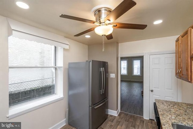 kitchen featuring light stone counters, plenty of natural light, stainless steel fridge, and dark wood-type flooring