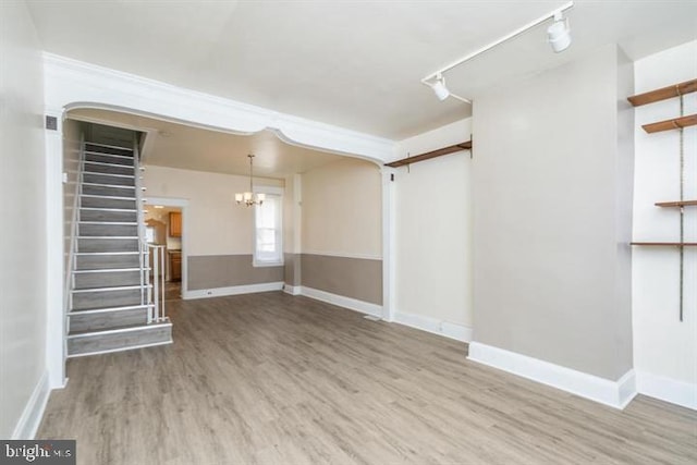 unfurnished living room with hardwood / wood-style flooring, rail lighting, and a chandelier