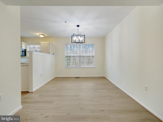 unfurnished dining area featuring light hardwood / wood-style floors and a notable chandelier