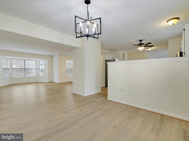 unfurnished living room featuring ceiling fan with notable chandelier and light hardwood / wood-style flooring