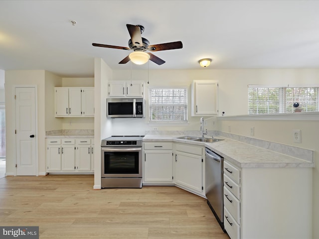 kitchen featuring appliances with stainless steel finishes, white cabinetry, sink, plenty of natural light, and light hardwood / wood-style flooring