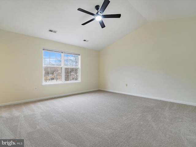 spare room with ceiling fan, vaulted ceiling, and light carpet