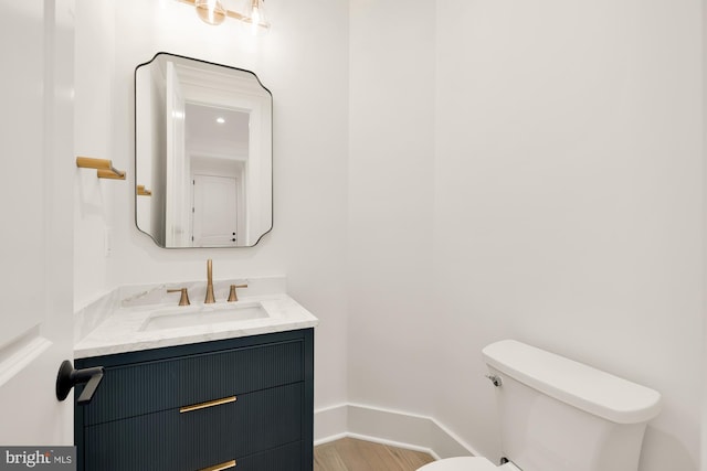 bathroom featuring toilet, wood finished floors, vanity, and baseboards