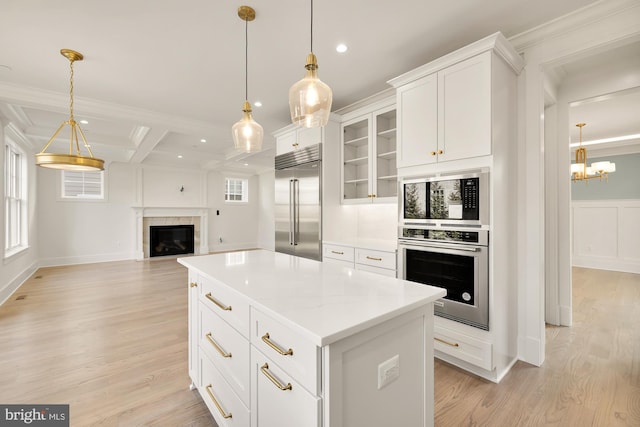 kitchen with built in appliances, light wood finished floors, open floor plan, and a fireplace