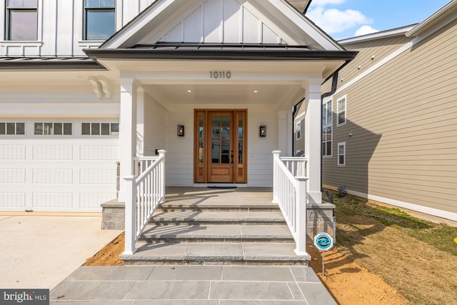 entrance to property featuring covered porch, board and batten siding, a standing seam roof, metal roof, and a garage