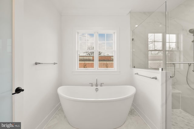 bathroom featuring a stall shower, marble finish floor, a freestanding bath, and baseboards