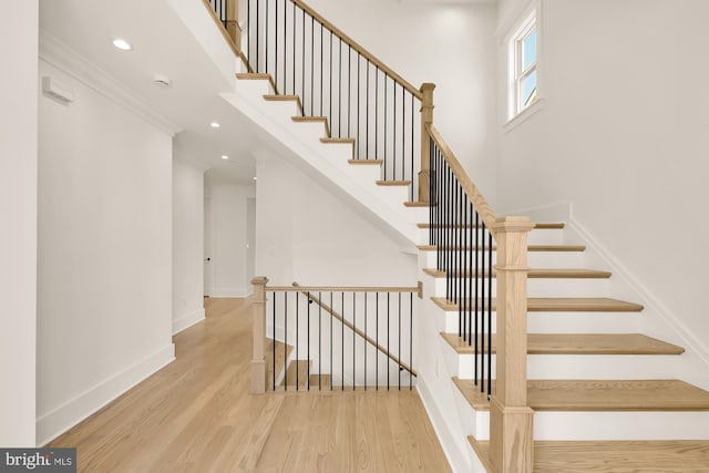 staircase with crown molding, recessed lighting, wood finished floors, and baseboards