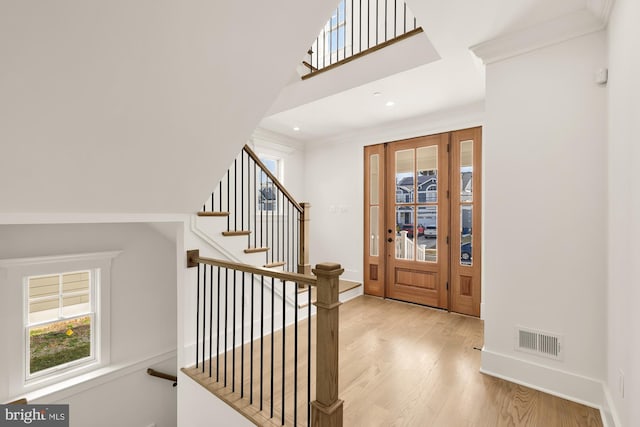 foyer entrance with baseboards, visible vents, wood finished floors, and ornamental molding