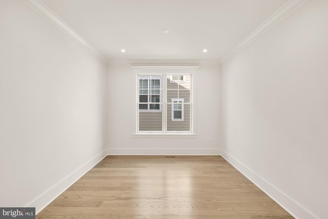 spare room featuring light wood finished floors, baseboards, and crown molding