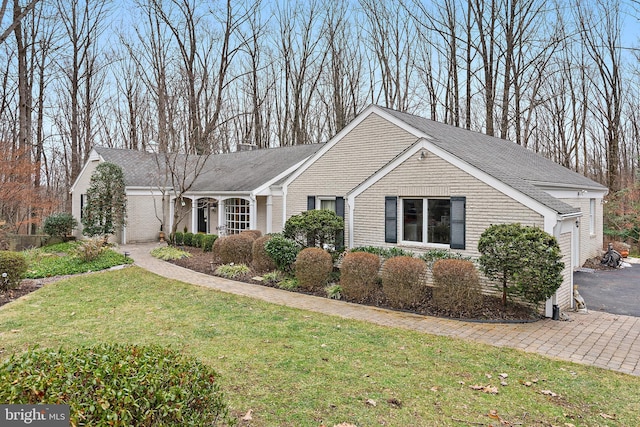 single story home with aphalt driveway, brick siding, an attached garage, and a front yard