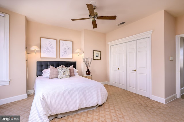 bedroom featuring light colored carpet, ceiling fan, and a closet