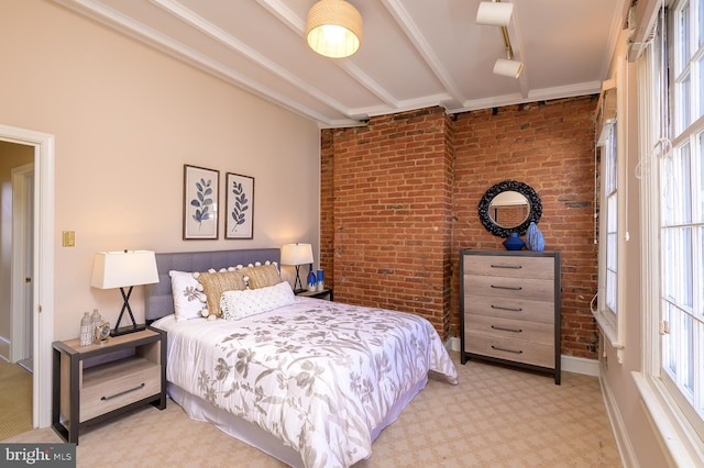 bedroom with multiple windows, track lighting, beamed ceiling, and brick wall