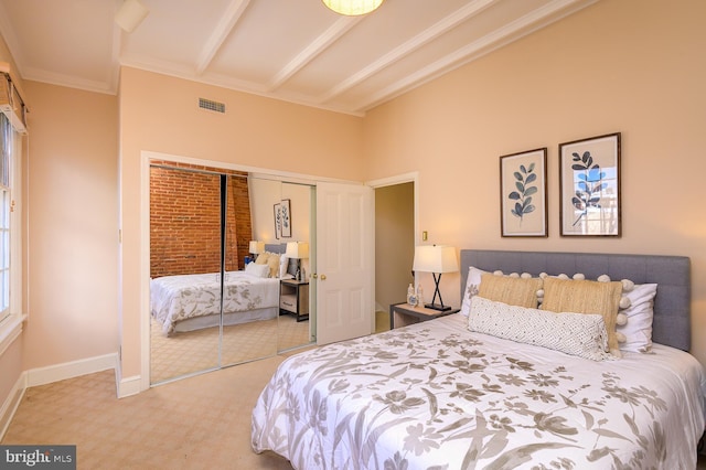 bedroom featuring beamed ceiling, ornamental molding, carpet flooring, and a closet