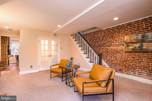 sitting room featuring brick wall, carpet floors, and french doors