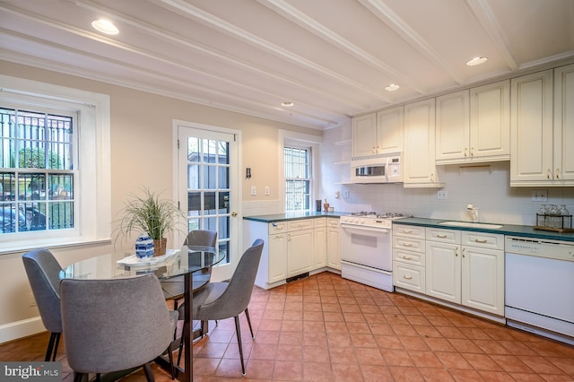 kitchen with sink, white appliances, tasteful backsplash, light tile patterned flooring, and beamed ceiling