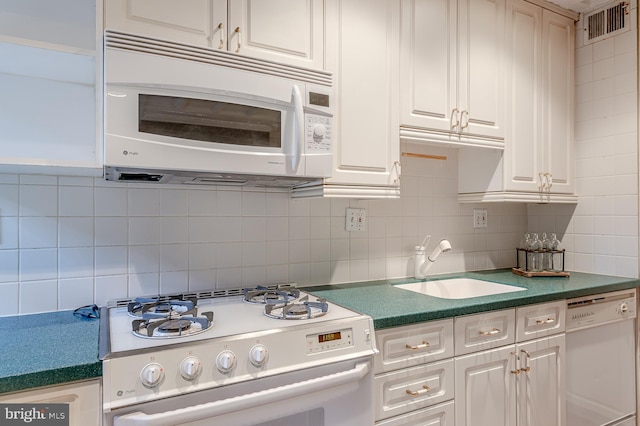 kitchen featuring tasteful backsplash, white cabinetry, sink, and white appliances