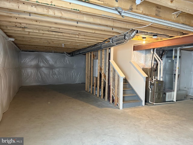 basement featuring electric panel and heating unit