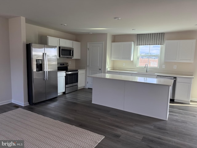 kitchen with sink, white cabinetry, a center island, appliances with stainless steel finishes, and dark hardwood / wood-style flooring