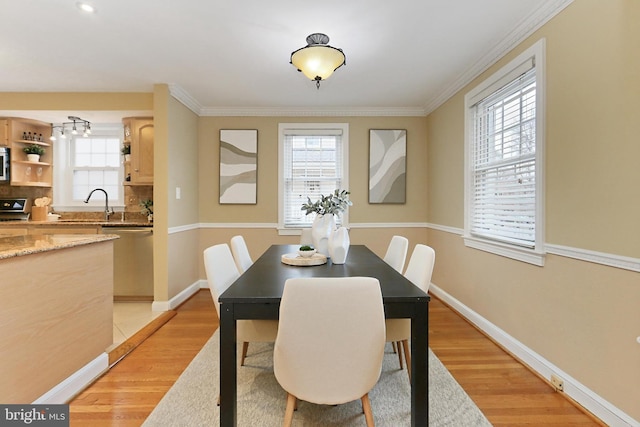 dining area featuring sink, crown molding, and light wood-type flooring